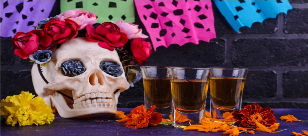 A skull with flowers on it and two glasses of tequila.